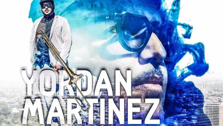 Affiche promotionnelle aux tons bleus mettant en vedette le musicien Yordan Martinez. On y voit un portrait rapproché de l’artiste portant des lunettes et une casquette, superposé à une image de lui tenant un trombone. Le texte mentionne “De Cienfuegos à Montréal !” ainsi que “TCMS – The Cuban Martinez Show”.