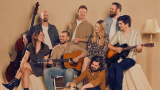 Affiche du spectacle « ENTRE NOUS – si on chantait encore… ». Groupe de personnes assises avec guitares et contrebasse. Texte : « 100 ans de chansons québécoises en spectacle ». Idéateur principal : Jason McNally. entrenousmusique.com